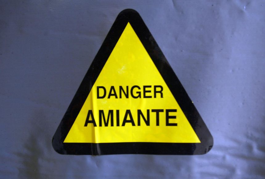 une bâche portant un symbole de danger couvre, le 02 juillet 2002 à Paris, un endroit d'un bâtiment où de l'amiante a été utilisé pour l'isolation.