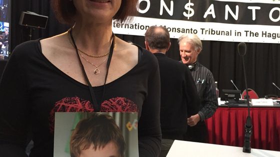 Sabine Grataloup avec le portrait du jeune Théo, en octobre 2016, au Tribunal Monsanto, à La Haye - Avec l'aimable autorisation de Rémi Barroux / Le Monde