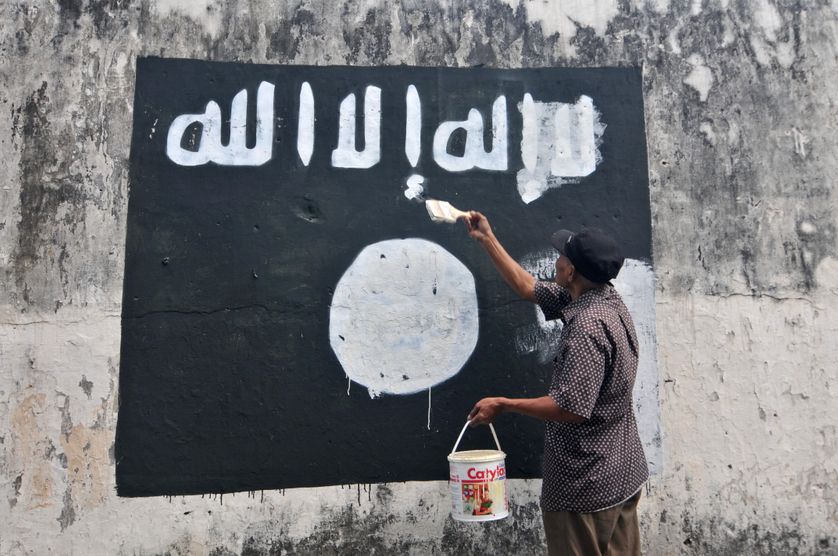 Un fonctionnaire indonésien efface les drapeaux de l’Etat islamique peints sur les murs de la ville de Surakarta (Java).