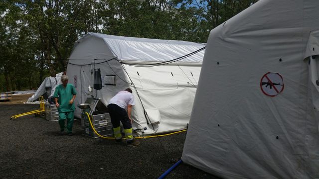 "L'hôpital de terrain de la Croix Rouge, en bordure des camps. A l'entrée des tentes où se reposent ou sont opérés des patients, un panneau interdit les armes"