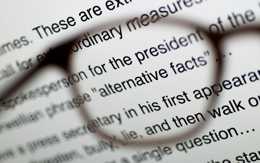 Une paire de lunette tenue devant un article en ligne à propos des soit disants « faits alternatifs » relatés par Trump.