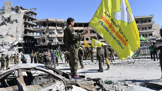 Soldats des FDS arborant leur drapeau dans les ruines de Raqqa libérée ©AFP - BULENT KILIC