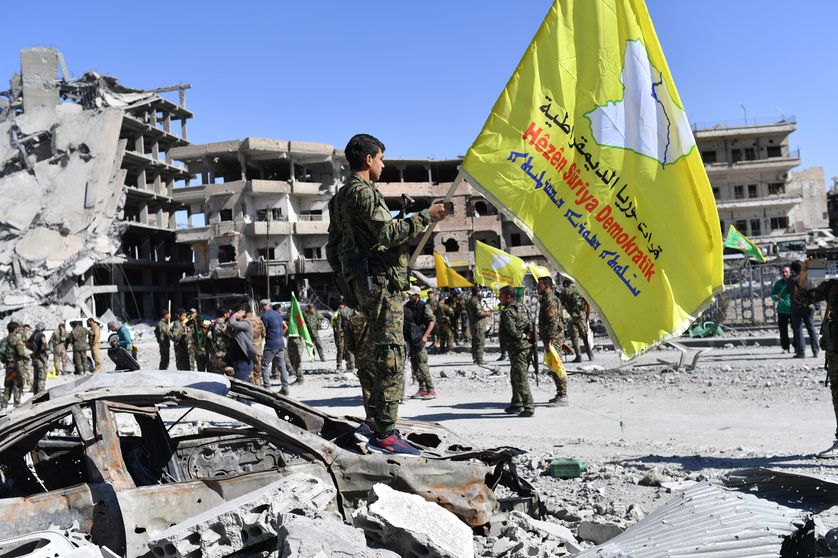 Soldats des FDS arborant leur drapeau dans les ruines de Raqqa libérée