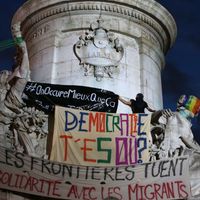 Un activiste grimpe sur le monument au centre de la place de la République avec la bannière "On occupe mieux que ça" (Nuit debout le 26 avril 2016 à Paris)