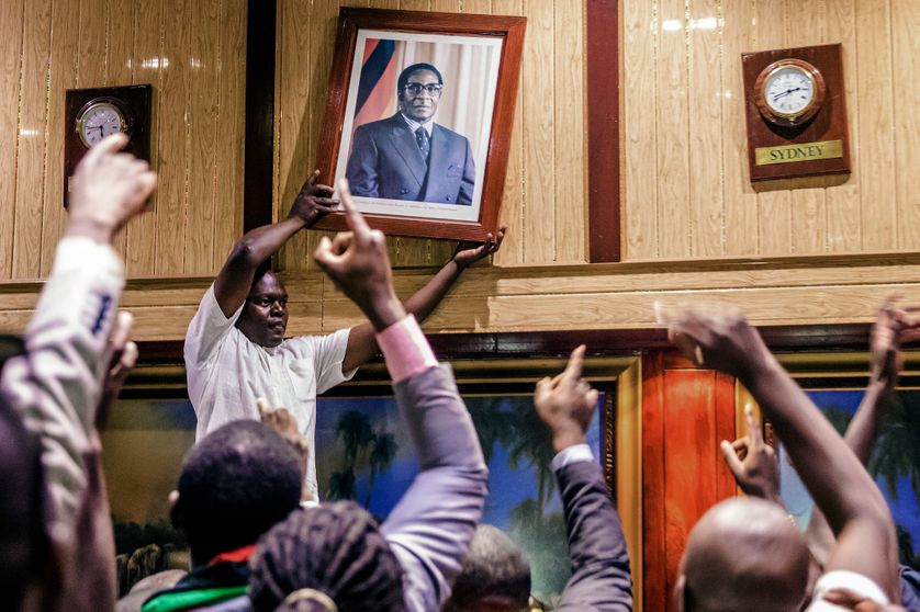 Des Zimbabwéens retirant le portrait de Robert Mugabe au Centre de conférence internationel, à l'annonce de sa démission