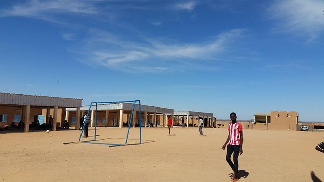 Dans la cour du centre de transit de l’OIM, des migrants jouent au football.