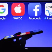 Un smartphone devant les logos des GAFA (acronyme de Google, Apple, Facebook et Amazon, les géants du web)
