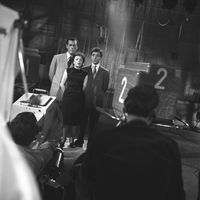 Edith Piaf entourée d'Eddie Constantine et de Charles Aznavour, sur le plateau de l'émission "XYZ". Première télévision d'Edith Piaf et de Charles Aznavour.