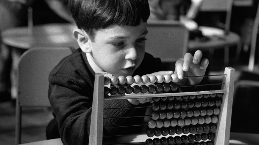 Un jeune garçon apprend à compter sur un boulier, dans une école primaire à Londres, en 1955
