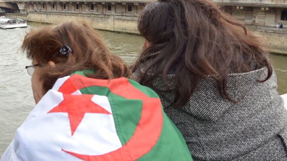 Une femme porte sur son dos le drapeau de l’Algérie, à Paris, en 2014, lors de la commémoration du Massacre du 17 octobre 1961. ©AFP - CITIZENSIDE / SAÏD ANAS