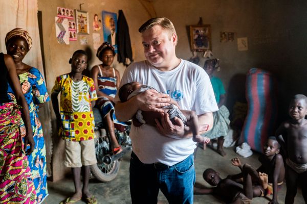 Mikko Franck dans le village de Houagon avec dans les bras Bellevie, nourrisson d'un mois suivi par la communauté du centre de santé local