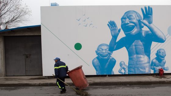 Travailleur chinois devant des visages moqueurs de Yue Minjun ©AFP - JOHANNES EISELE