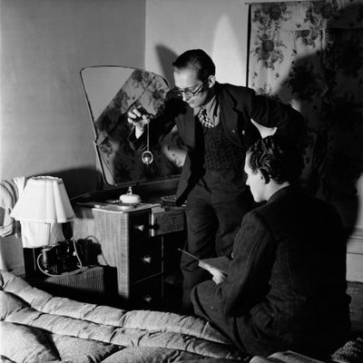 Un membre du Club des Chasseurs de Fantômes utilise une boussole et un pendule pour détecter des phénomènes paranormaux dans une chambre d'une ferme hantée.