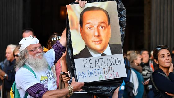 Photomontage des portraits de Silvio Berlusconi et de Matteo Renzi tenue par un partisan du Mouvement 5 étoiles, lors d’une manifestation contre la loi électorale votée en octobre 2017. ©AFP - Alberto Pizzoli
