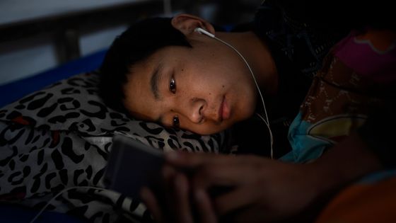 Un homme regarde son smartphone avant de s'endormir ©AFP - WEI LIANG / IMAGINECHINA