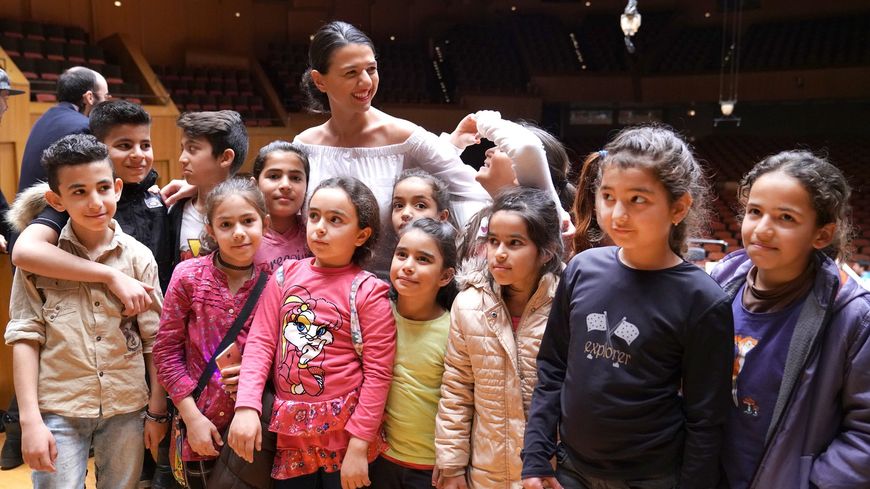 Au Megaron d'Athènes, la pianiste Khatia Buniatishvili en compagnie d'enfants vivant dans les camps de réfugiés et faisant partie d'El Sistema Greece