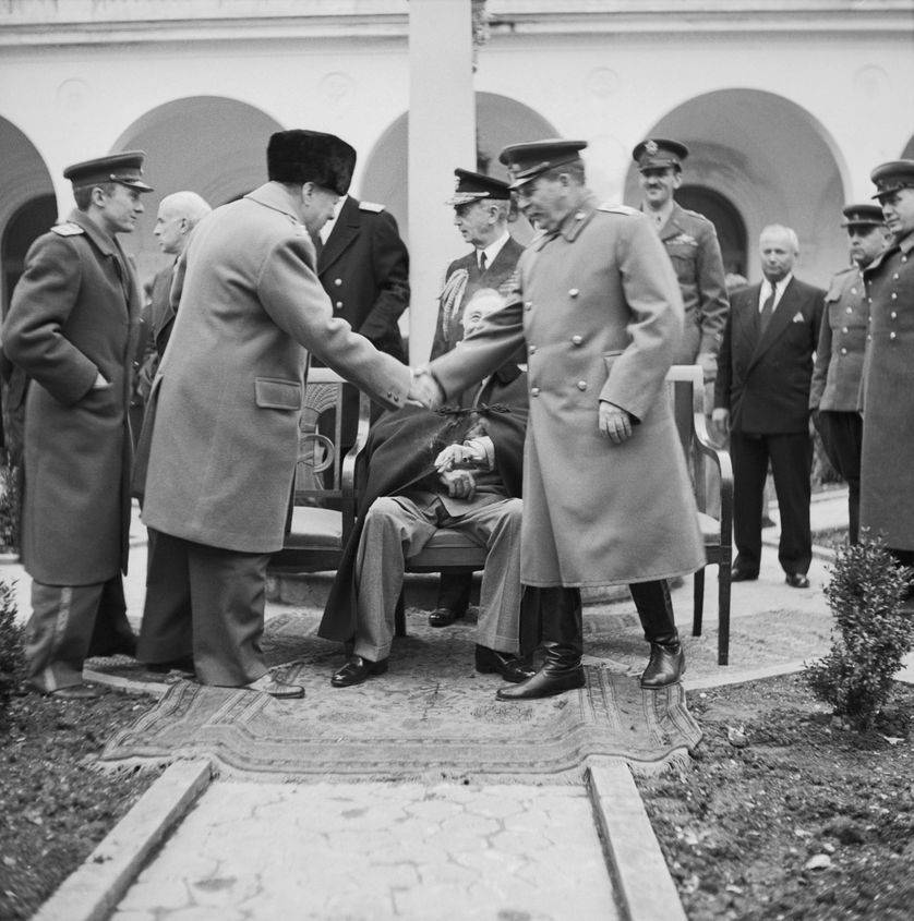 La Conférence de Yalta en février 1945, Winston Churchill serre la main de Staline. Le président Roosevelt est assis derrière.