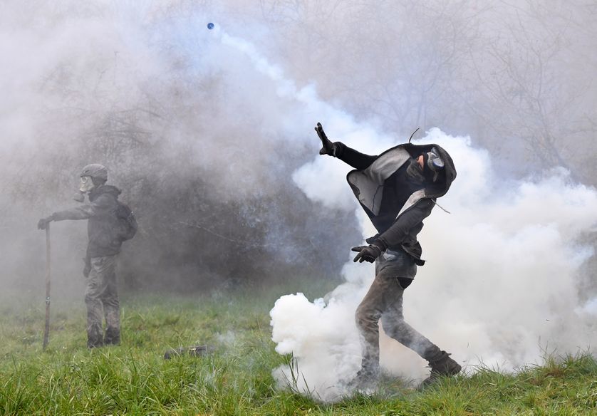 Un protestant lance une cartouche de gaz lacrymogène contre les forces de l'ordre à Notre-Dame-des-Landes le 10 avril 2018