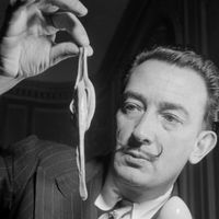 Photo prise dans les années 50 du peintre espagnol Salvador Dali présentant la "montre molle".