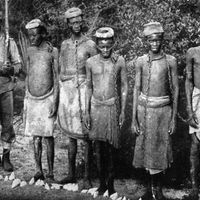 Vers 1896: Des esclaves enchaînés, gardés par un Askari indigène