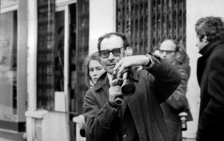 Caméra à la main, le cinéaste Jean-Luc Godard filme une manifestation en mai 1968 à Paris