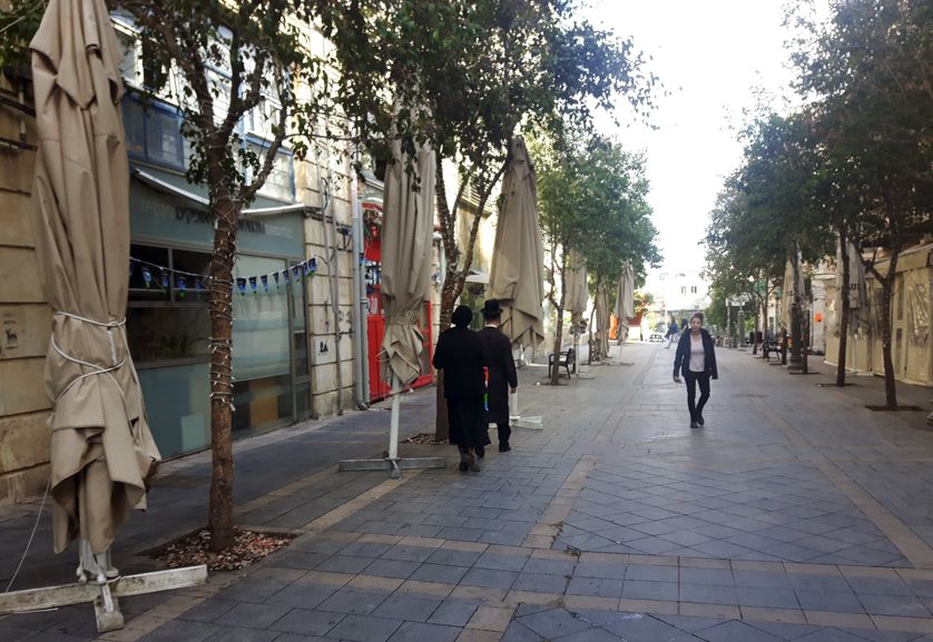 Un couple et une jeune femme dans une rue déserte en pleine après-midi d'un samedi, shabbat