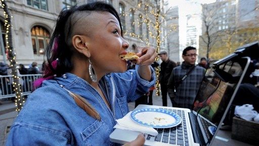 Sade Adona croque une bouchée de tarte à la citrouille pendant que les manifestants d'Occupy Wall Street mangent des dîners de Thanksgiving servis à Zuccotti Park à New York (le 24 novembre 2011). ©AFP - Stan Honda