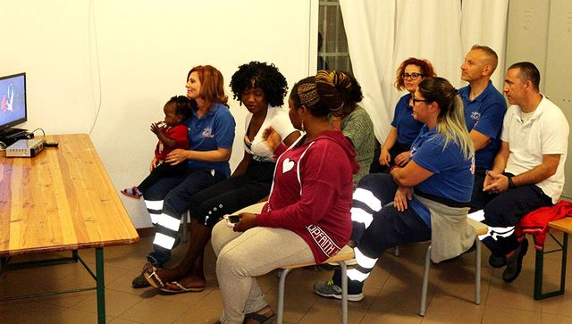 Le personnel du centre, Gwen la médiatrice et Mercy et sa maman Taiwo attendent la chanson de Madame Monsieur à l’Eurovision
