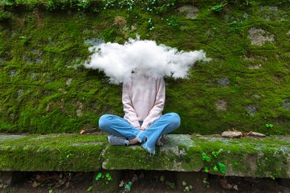 Femme jeune avec la tête assise sur un banc avec la tête entourée d'un nuage Femme jeune avec la tête assise sur un banc avec la tête entourée d'un nuage