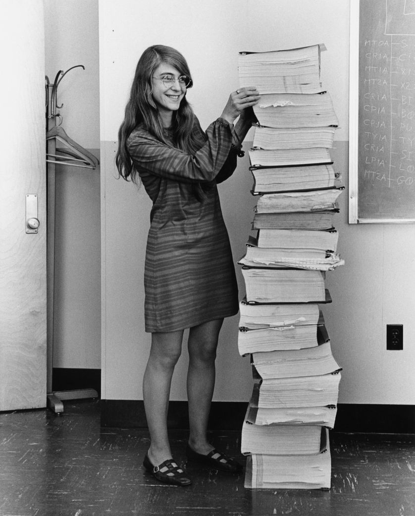 Margaret Hamilton se tenant auprès du code du logiciel de navigation qu'elle et son équipe ont produit pour le programme Apollo.