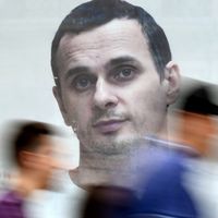 Les gens passent devant une affiche avec une photo du réalisateur ukrainien Oleg Sentsov, prise par le journaliste Anton Naumlyuk,