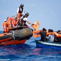 Une photo de SOS Méditerranée, publiée le 14 août. Des membres de l'équipages de l'Aquarius remettent des gilets de sauvetage aux migrants au large des côtes libyennes (10/08/2018).