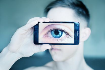 Gros plan d'un œil humain à travers un téléphone portable. Gros plan d'un œil humain à travers un téléphone portable.