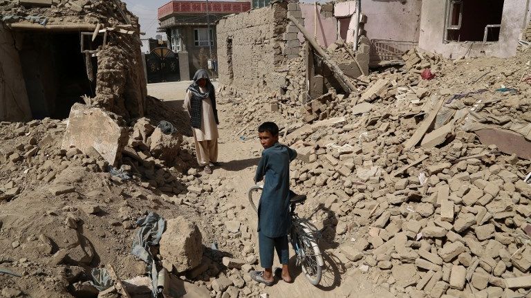 Les habitants afghans marchent près des maisons détruites après une attaque des talibans à Ghazni le 16 août 2018.