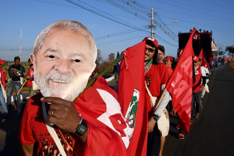Les membres du Mouvement des paysans sans terre portant des masques de l'ancien président brésilien Luiz Inacio Lula da Silva, participent à la marche "Free Lula" près de Brasilia, le 14 août 2018.