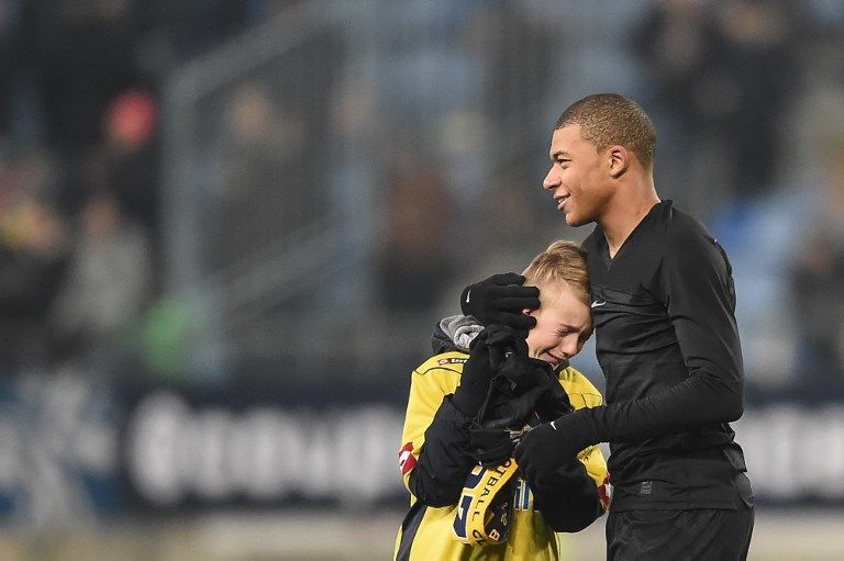 L’attaquant français du Paris Saint-Germain Kylian Mbappe (D) remet son maillot à un enfant après le match de Coupe de France entre Sochaux (FCSM) et le Paris Saint-Germain (PSG) le 6 février 2018.
