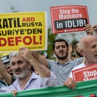 : Turkish muslim men hold placards and chant slogans during a protest against a Syrian military operation in the rebel-held Idlib province of northwest Syriain front of the Fatih mosque in Istanbul on September 7, 2018.