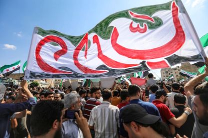 Des Syriens de la ville d'Idlib et des villes environnantes, agitent une bannière aux couleurs de l'opposition pendant une manifestation anti-gouvernementale sur une place principale à Idlib le 14 septembre 2018. Des Syriens de la ville d'Idlib et des villes environnantes, agitent une bannière aux couleurs de l'opposition pendant une manifestation anti-gouvernementale sur une place principale à Idlib le 14 septembre 2018.
