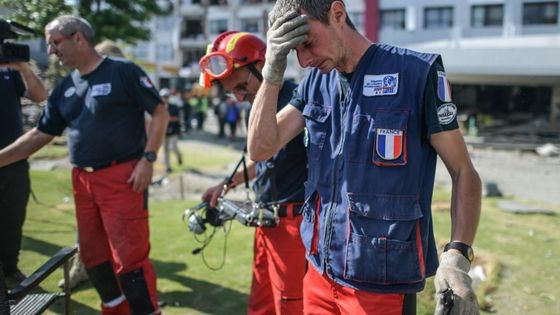 Des membres de l'ONG Pompiers de l'Urgence Internationale quittent l'hôtel Mercure gravement endommagé après des opérations de recherche et sauvetage à Palu en Indonésie, le 5 octobre 2018, à la suite du séisme et du tsunami. ©AFP - MOHD RASFAN / AFP