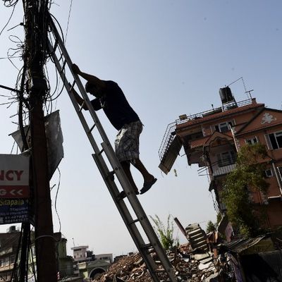 Un Népalais descend d'une échelle à Katmandou après avoir réparé du câblage près d'une maison laissée dans une situation précaire après le tremblement de terre qui a frappé la nation himalayenne le 25 avril 2015.