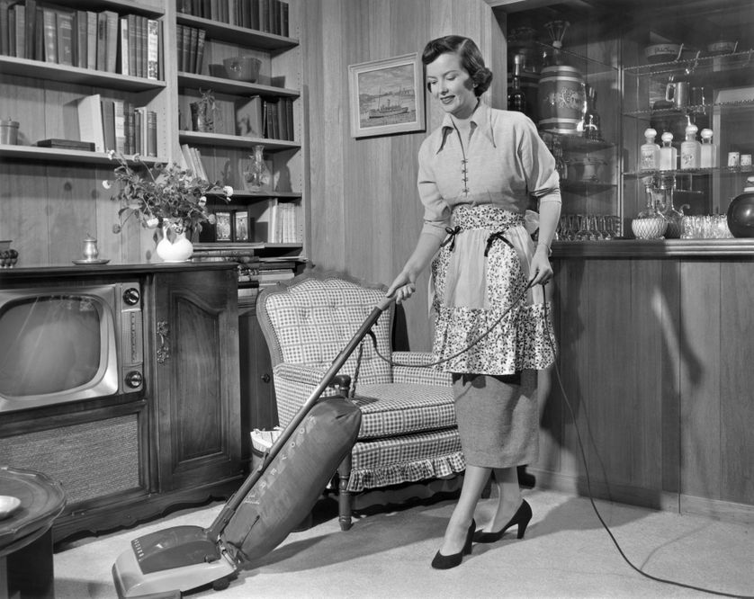 En 1950, une femme passe l'aspirateur dans son intérieur