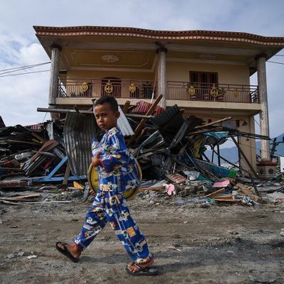 Un garçon se promène devant des débris de tsunami entassés à côté d'un bâtiment encore debout à Palu, en Indonésie, quelque jours après le tremblement de terre et le tsunami qui ont frappé la région le 28 septembre.