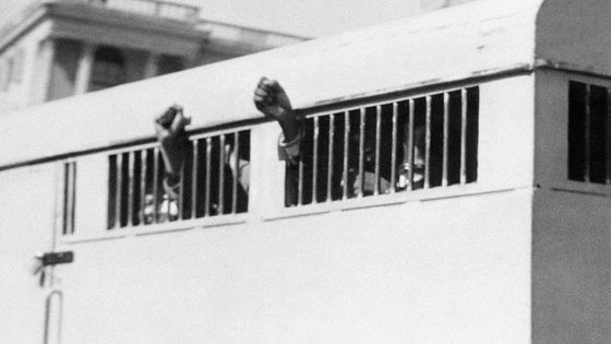 Les huit membres de l'ANC, parmi lesquels Nelson Mandela, condamnés à la prison à perpétuité pour terrorisme lors du procès de Rivonia, levant le poing à travers les barreaux du fourgon de transfert, Pretoria, 12 juin 1964 ©AFP