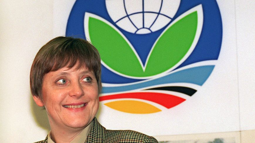 Angela Merkel en mars 1995 devant le logo de la Conférence de l'ONU sur le climat. La future chancelière est alors ministre de l'environnement et chargée d'organiser la COP1 de Berlin.