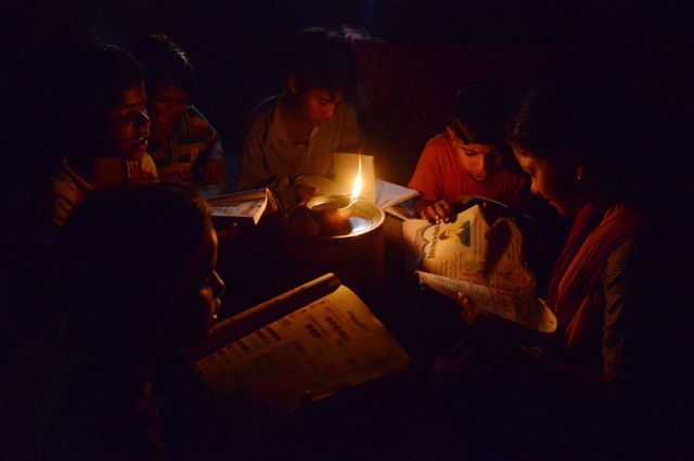 Des écoliers indiens du Pendjab lisent à la lumière d’une bougie faute d’accès à l’électricité.