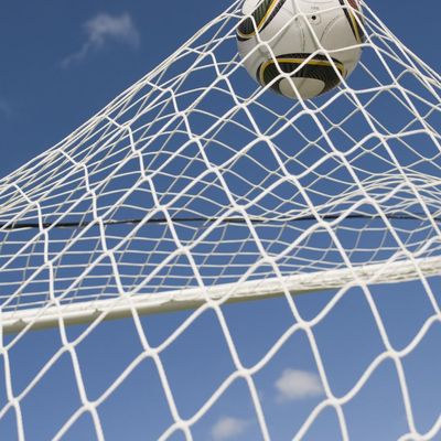 Un ballon au fond des filets sur un terrain de football.