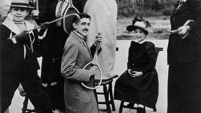 Marcel Proust à genoux, tenant une raquette de tennis devant Jeanne Ponquet debout sur une chaise, au tennis du Boulevard Bineau à Neuilly en 1892