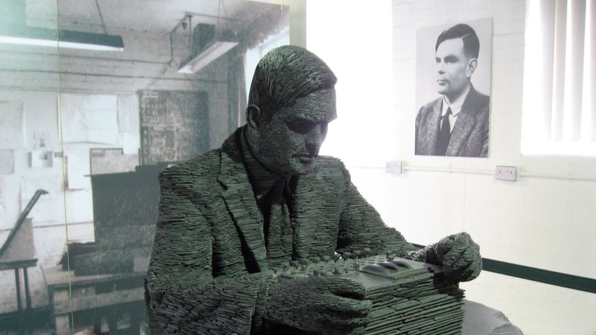 Alan Turing, portrait (au fond) et sculpture , composée d’environ un demi-million de pièces en ardoise du Pays de Galles, oeuvre de Stephen Kettle sur une commande de Sidney Frank