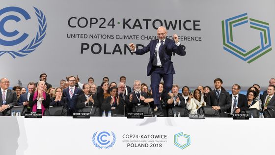 Le président polonais de la COP24, Michal Kurtyka, saute sur la table lors de la clôture de la conférence climat, le 15 décembre 2018 à Katowice. ©AFP - JANEK SKARZYNSKI