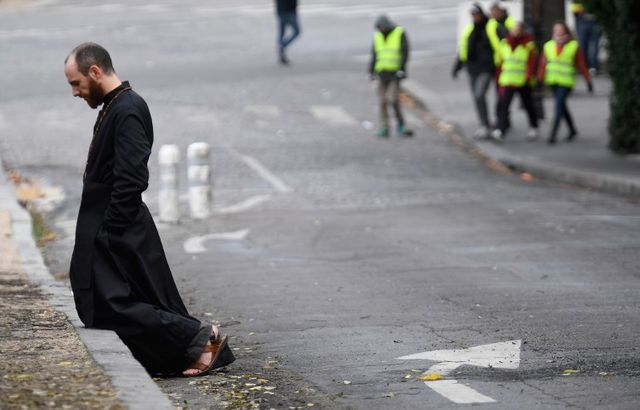 Scène inattendue samedi 8 décembre 2018 sur les Champs-Elysées : un prêtre agenouillé sur le trottoir